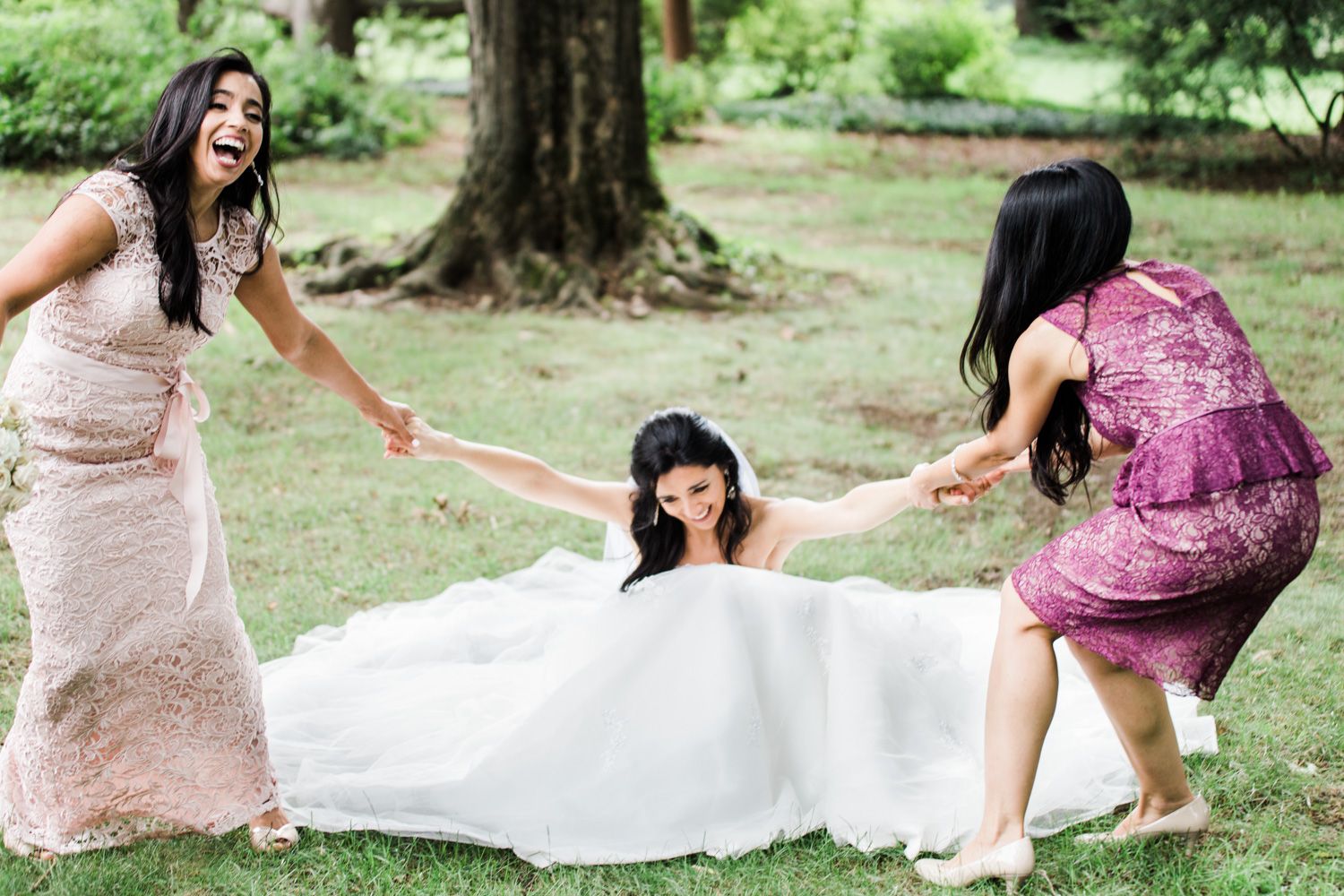 Bridesmaids help bride get up from the ground in a candid photo