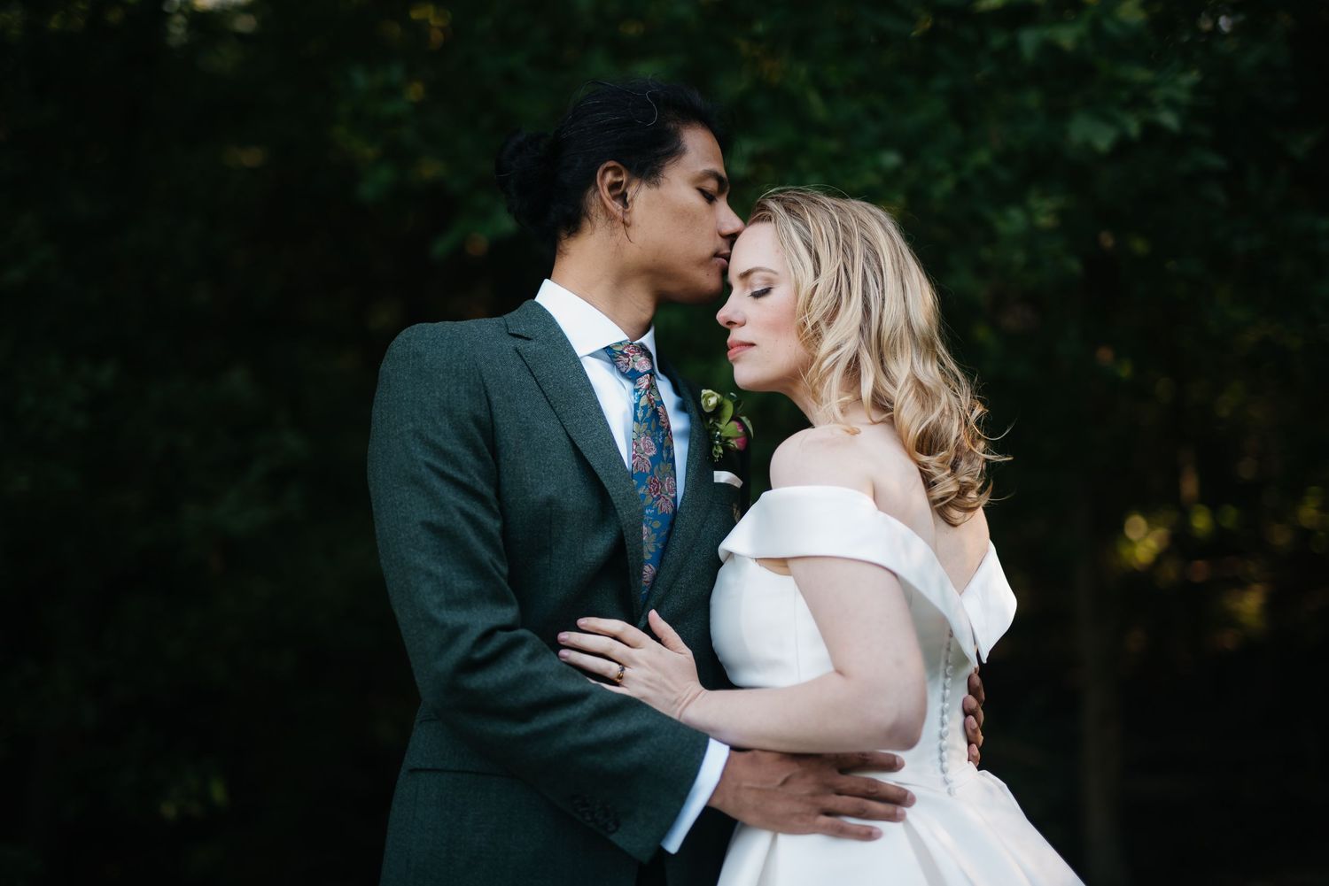 A romantic wedding portrait of a couple sharing a tender moment in a garden setting.