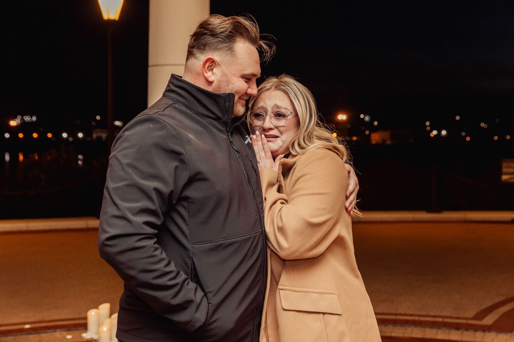 A tender moment shared between a couple in winter coats beneath illuminated columns.
