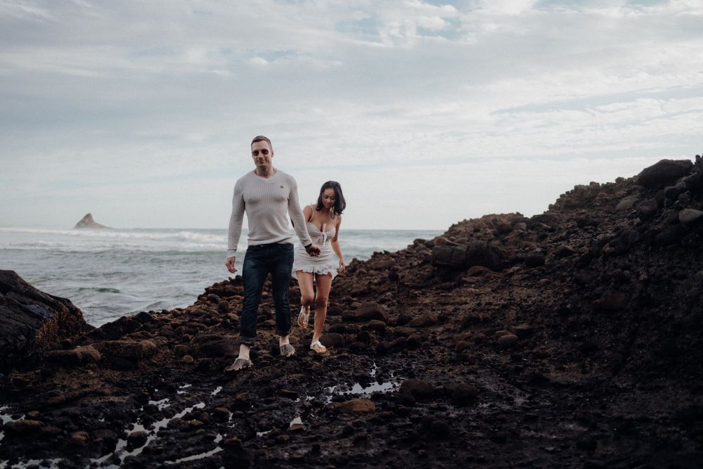 A couple explores volcanic rocks along a dramatic coastline.