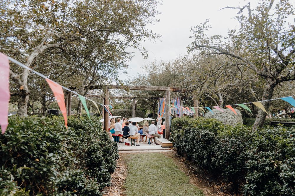 Garden pathway decorated with colorful bunting and lined with hedges for an outdoor wedding.