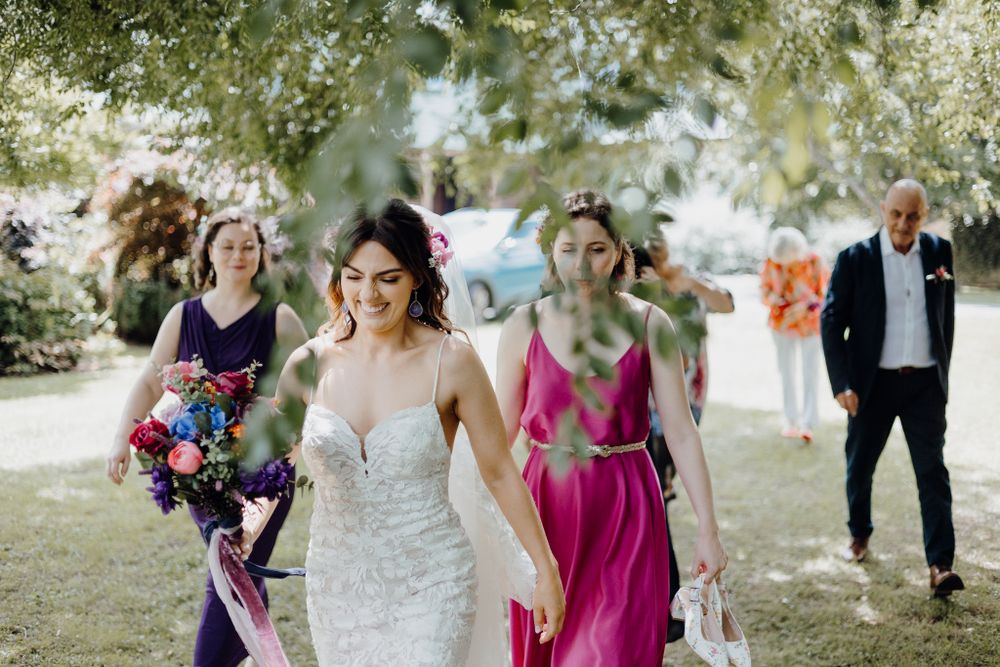 Wedding party walking outdoors with bright floral bouquets and colorful formal attire.