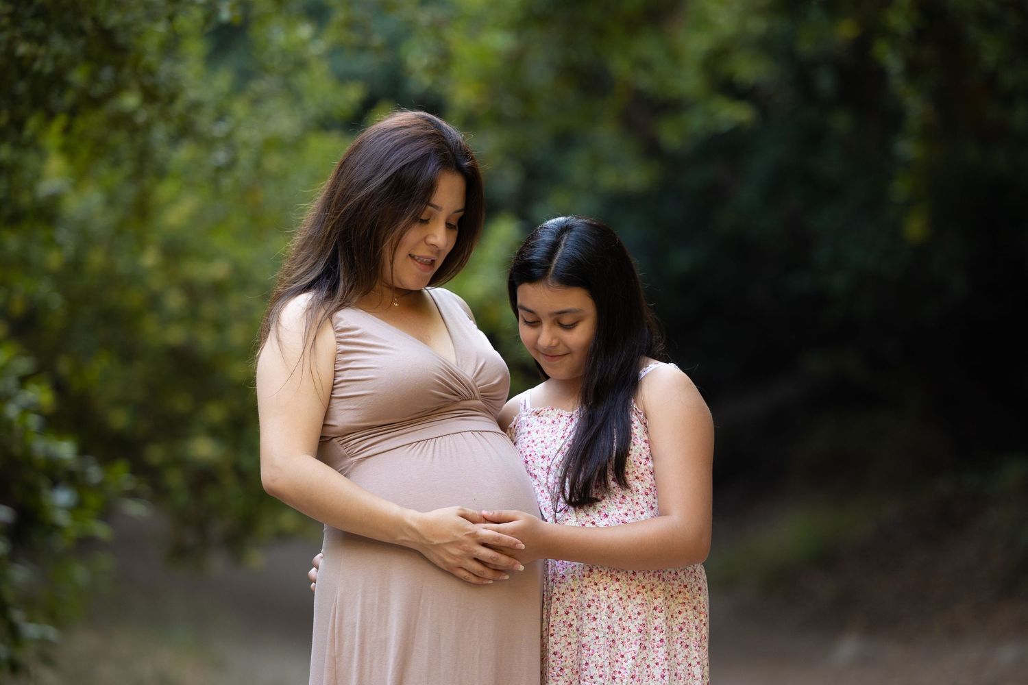 mother and daughter looking at mom's pregnant belly