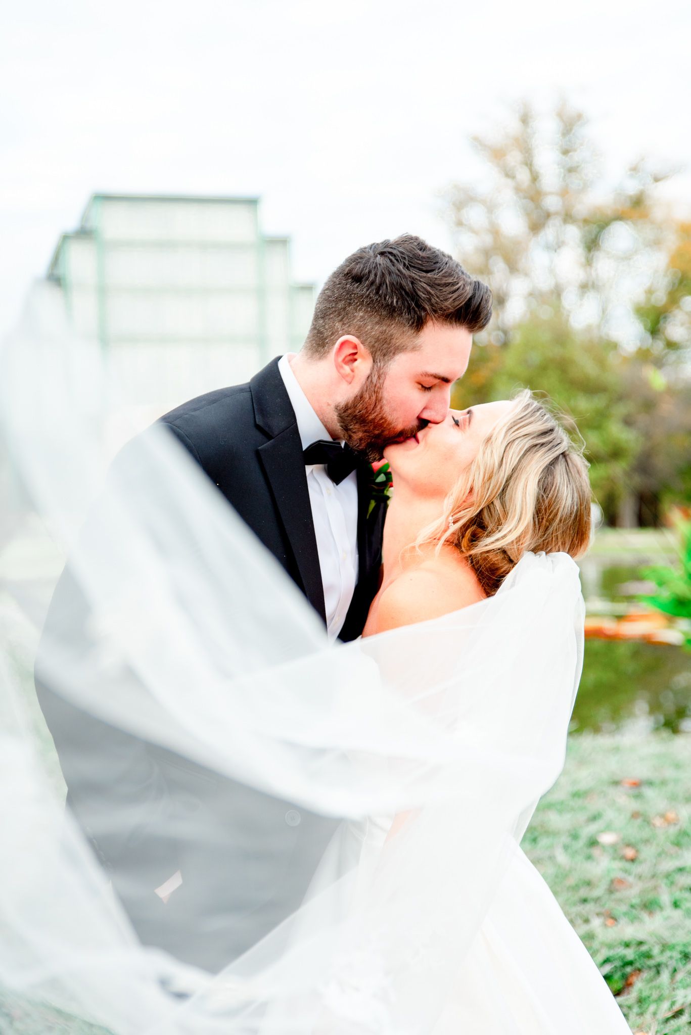 bride and groom kissing with veil in pictures on fall wedding day