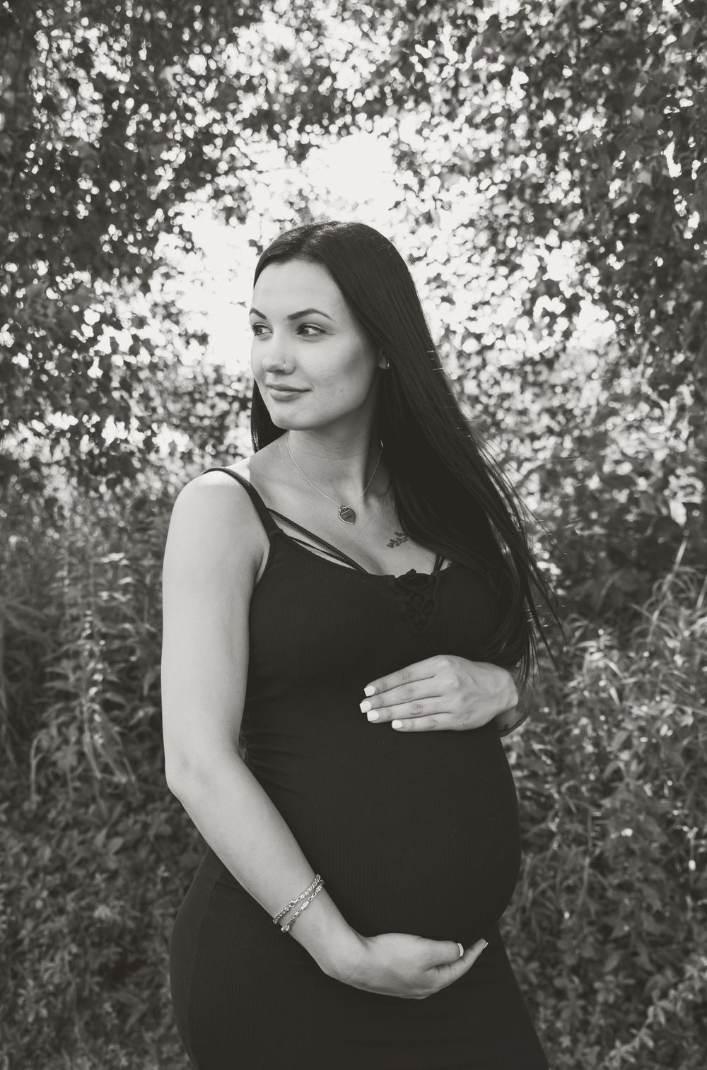 maternity photo of woman holding belly in woods
