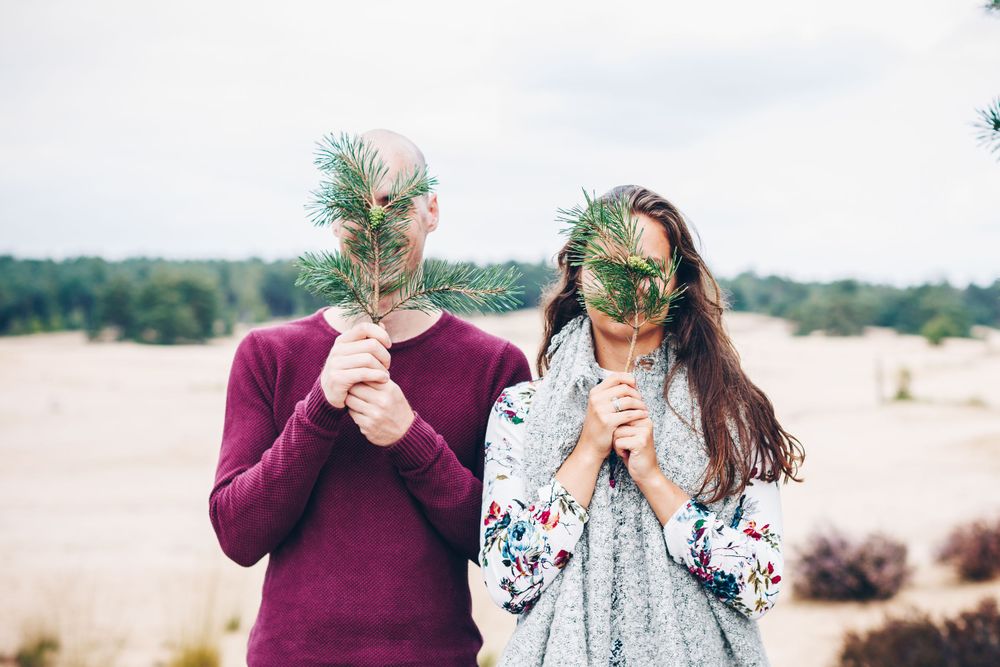 Man en vrouw met blad voor gezicht in de natuur