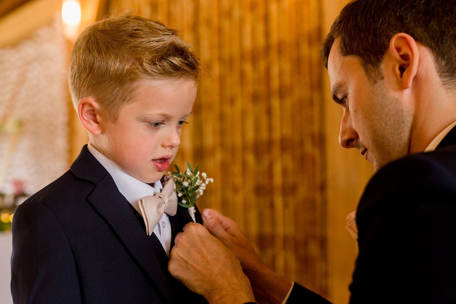 groom helping ring bearer with botton hole