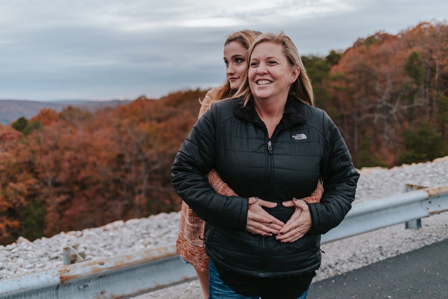 A daughter stands behind her mother with her hands on her waist