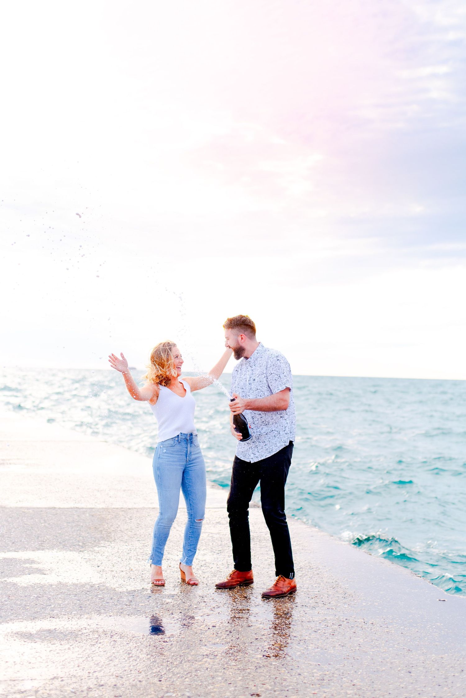 engaged couple in Chicago pops champagne at sunrise at North Avenue Beach pier