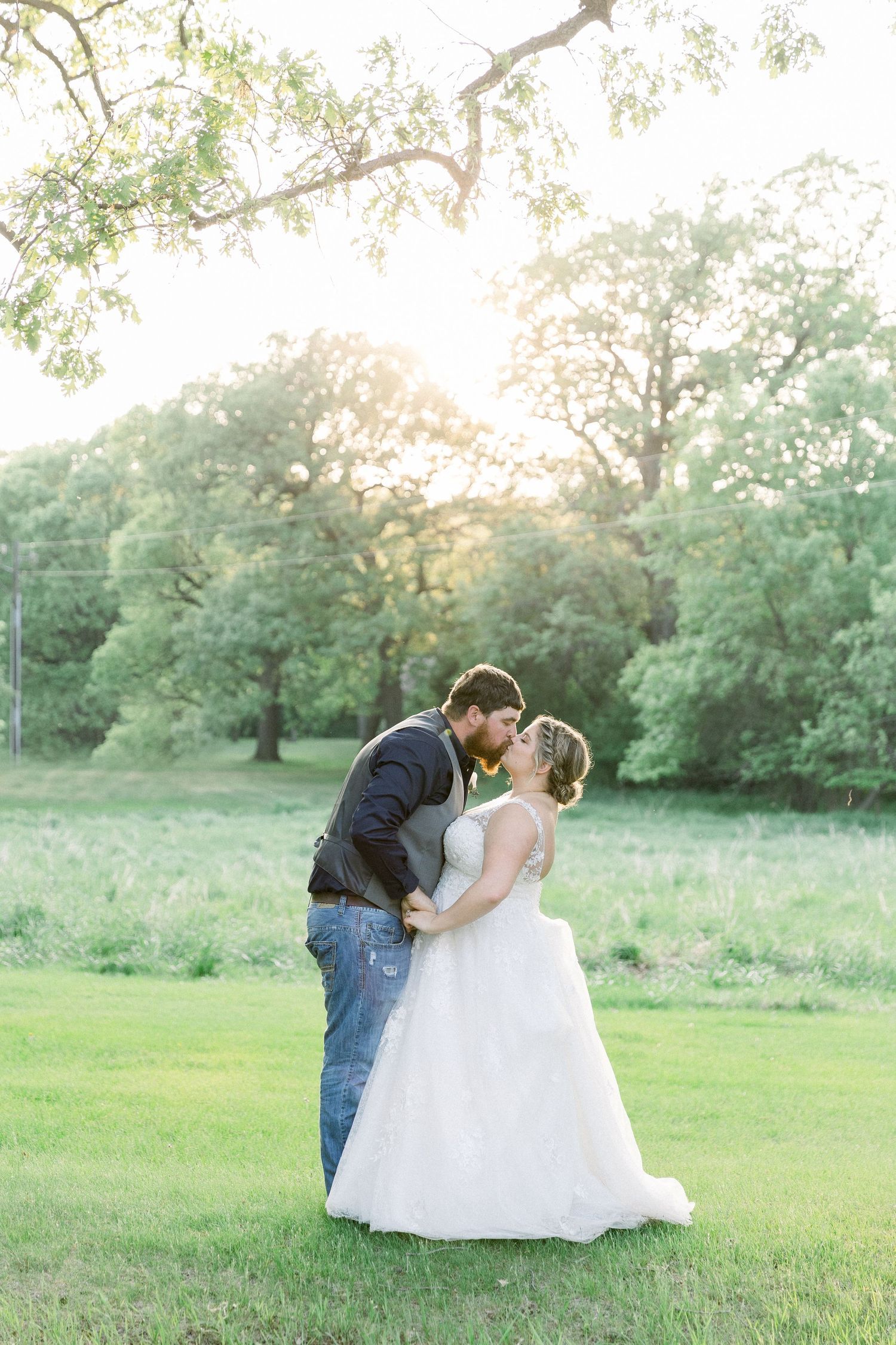 Bride and groom kissing in field