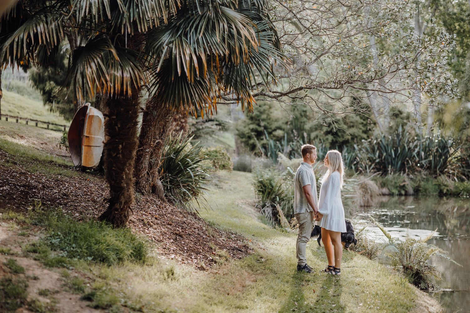 A scenic garden pathway with palm trees and a pond creates a romantic tropical setting.