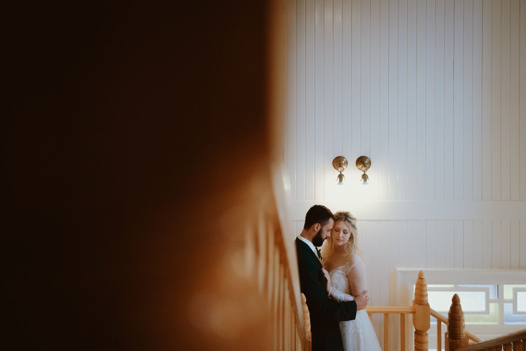 Silhouette of a couple standing intimately by a wall with soft lighting.