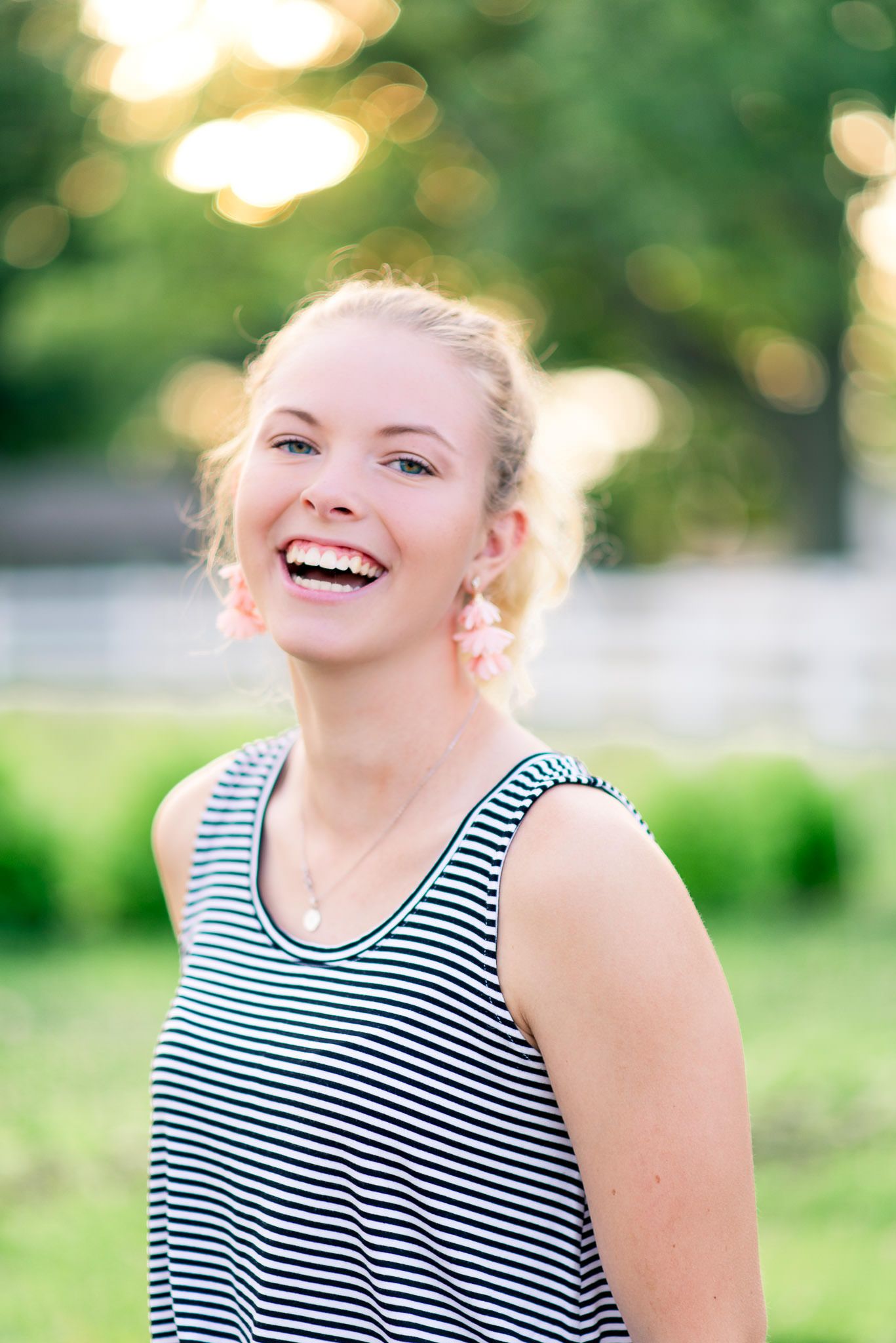 blonde young woman with blue eyes laughing in front of trees at sunset at the Marmalade Lily