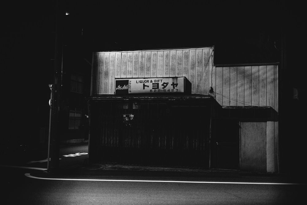 Minimalist black and white exterior of a closed shop at night.