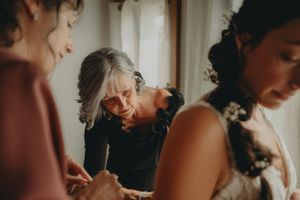 Emotional candid moment captured during wedding preparations in soft window light.
