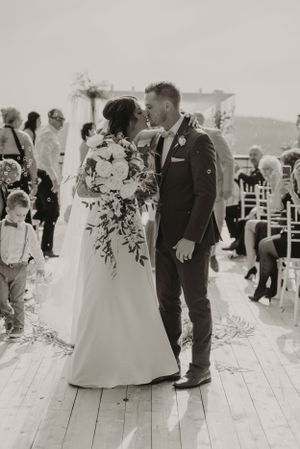 A romantic black and white wedding photo of a couple sharing their first dance on a wooden deck.