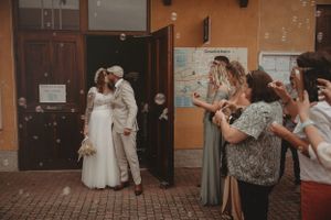 Wedding celebration outside a building with guests throwing confetti.