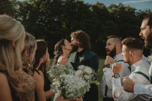 Wedding party celebrating outdoors with white baby's breath bouquets at sunset.
