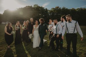 Wedding party poses together in outdoor setting during golden hour.