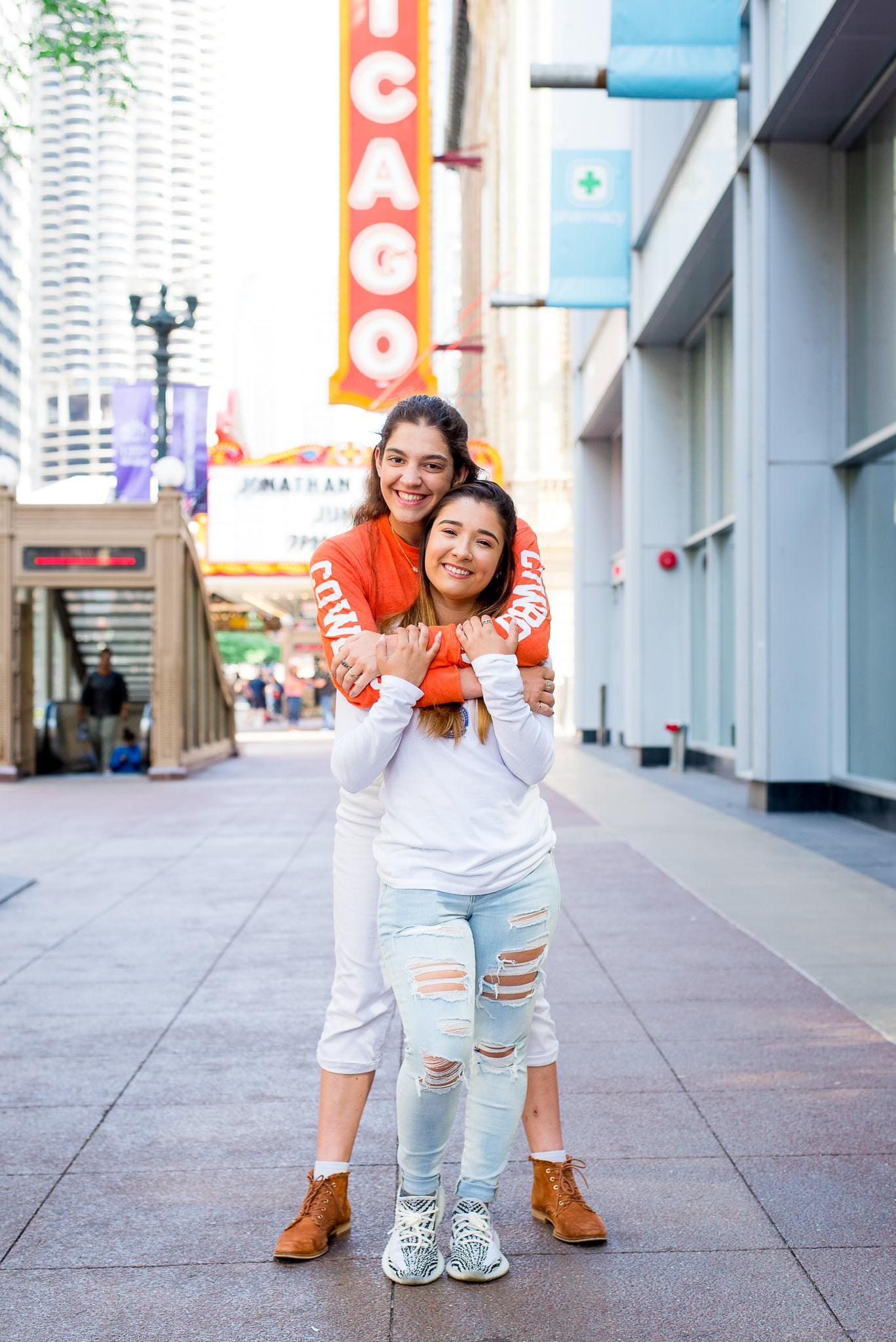 two senior girls in front of the Chicago Theater sign for Chicago senior pictures hugging each other