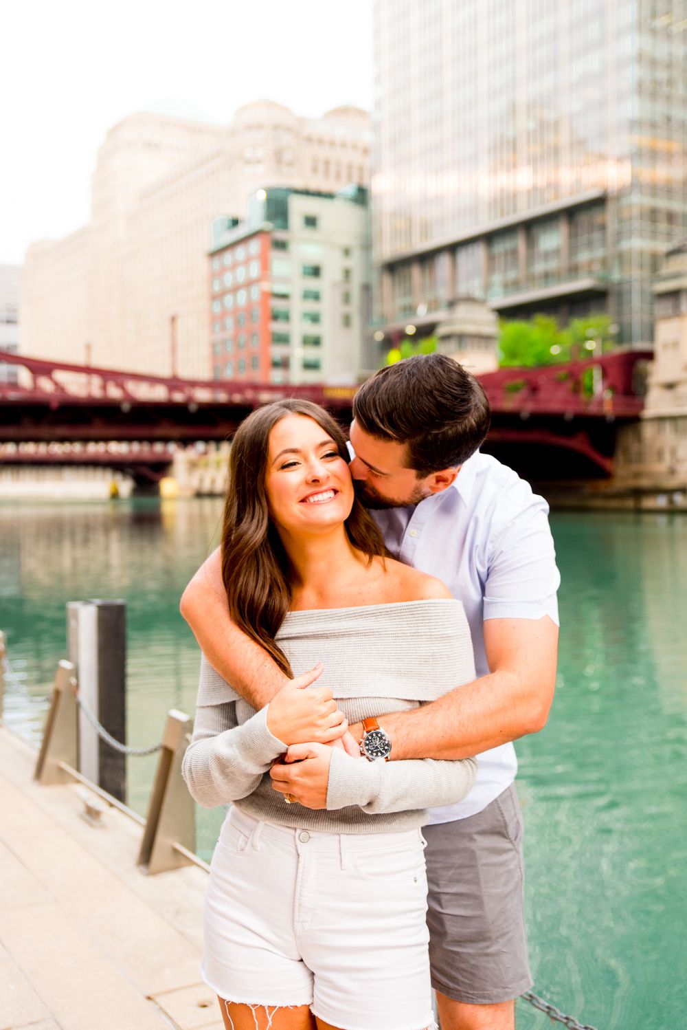 man in short sleeves shirt hugging fiance from behind at the Chicago Riverwalk