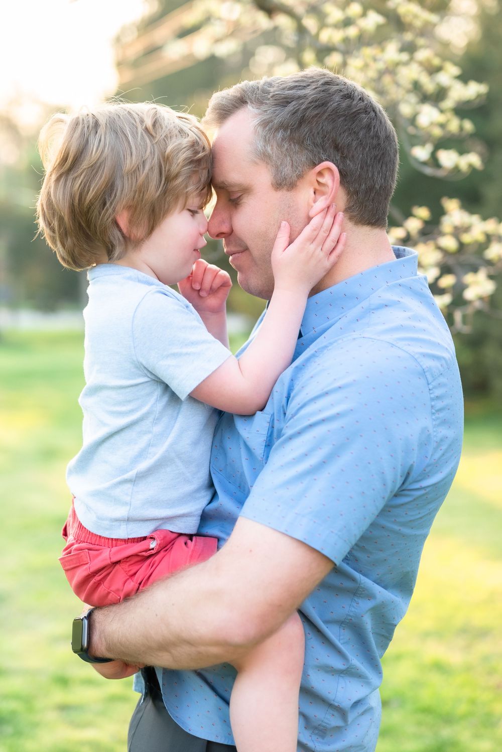 Tender moment between parent and child embracing outdoors in springtime setting.