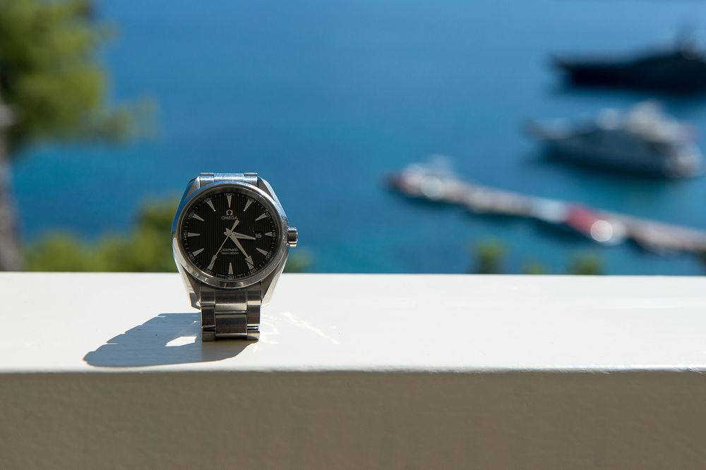 groom's omega watch in front of the blue sea of poros