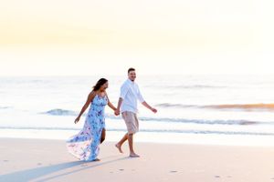 couple holding hands and walking alongside the water at North Avenue Beach Chicago during sunrise