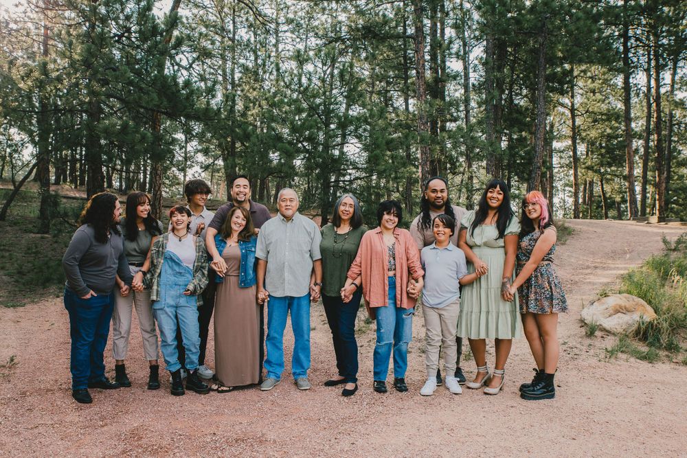 An extended family group poses in a forest setting for a family portrait.