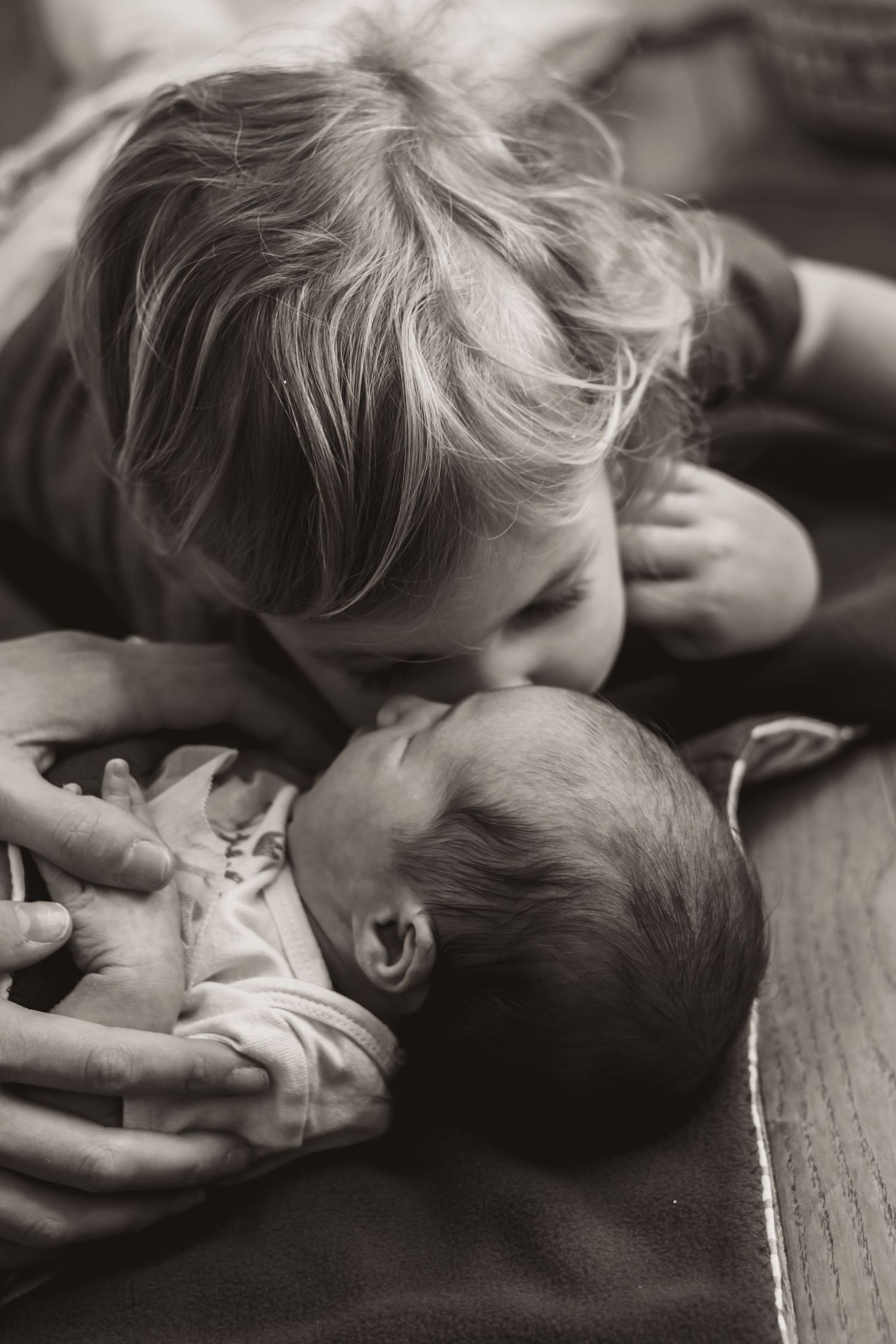 Toddler kissing her new baby sister