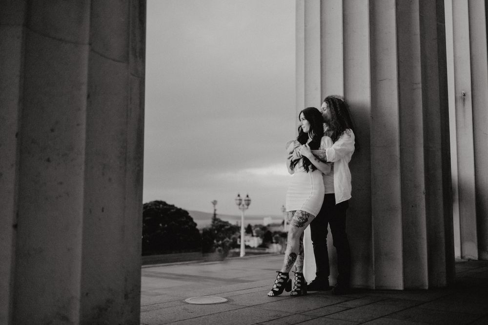 Black and white photo of a couple between classical columns with architectural elements.