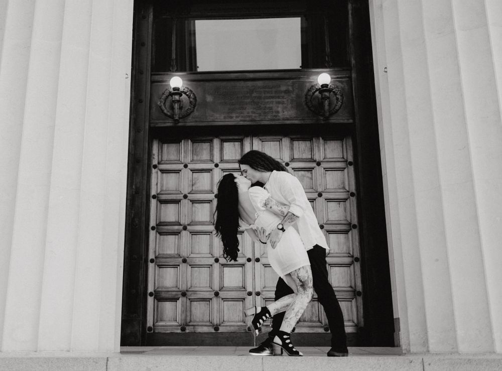 Romantic black and white photograph in front of an ornate wooden door.