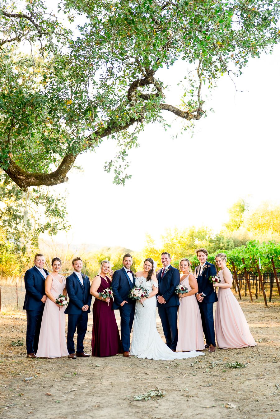 navy and blush wedding party smiles under huge oak tree on Pennyroyal Farm California Vineyard