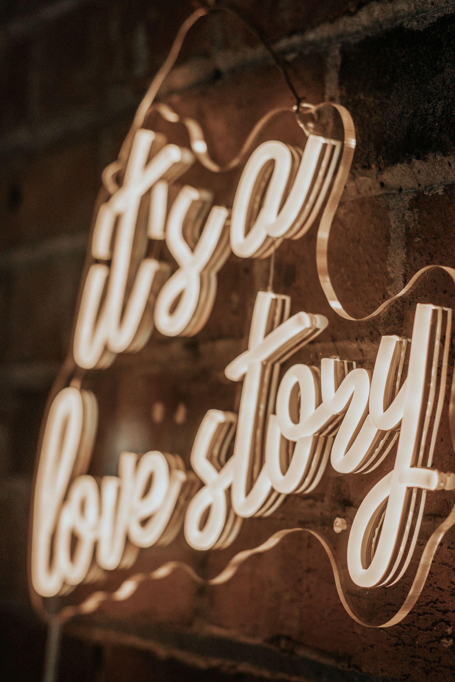 Illuminated neon love story sign on brick wall creating warm ambient glow.