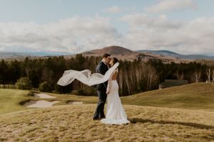 Husband and wife embracing each other and kissing with a view of the white mountains in the background.