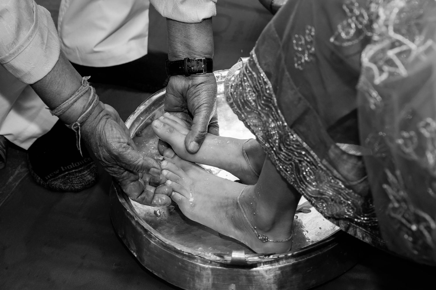 Black and white image of traditional foot washing ritual during Hindu ceremony.