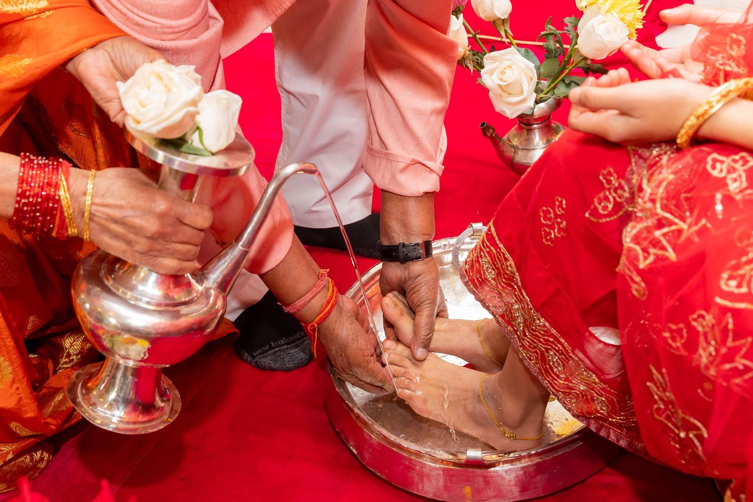 Traditional Hindu ceremony ritual with silver vessels and red decorative elements.