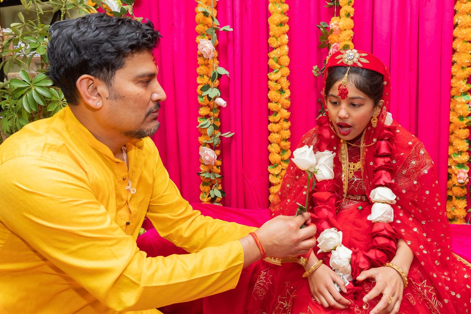 Traditional Hindu ceremony ritual with participants in red and yellow attire performing customs.