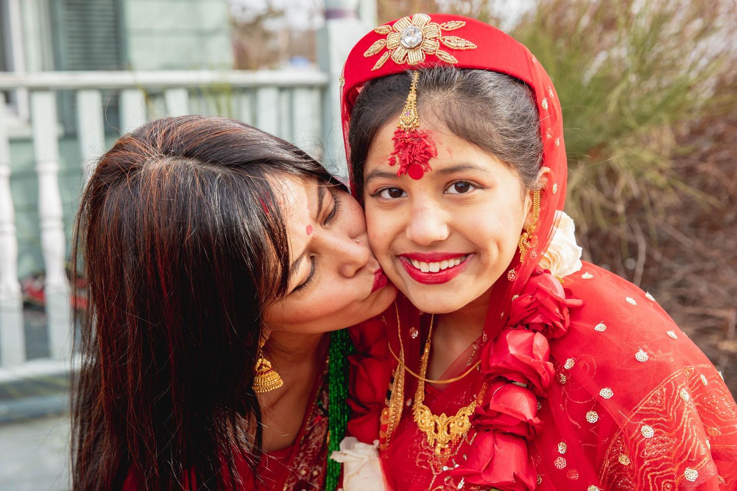 Celebration moment showing affection during traditional Hindu ceremony in red attire.