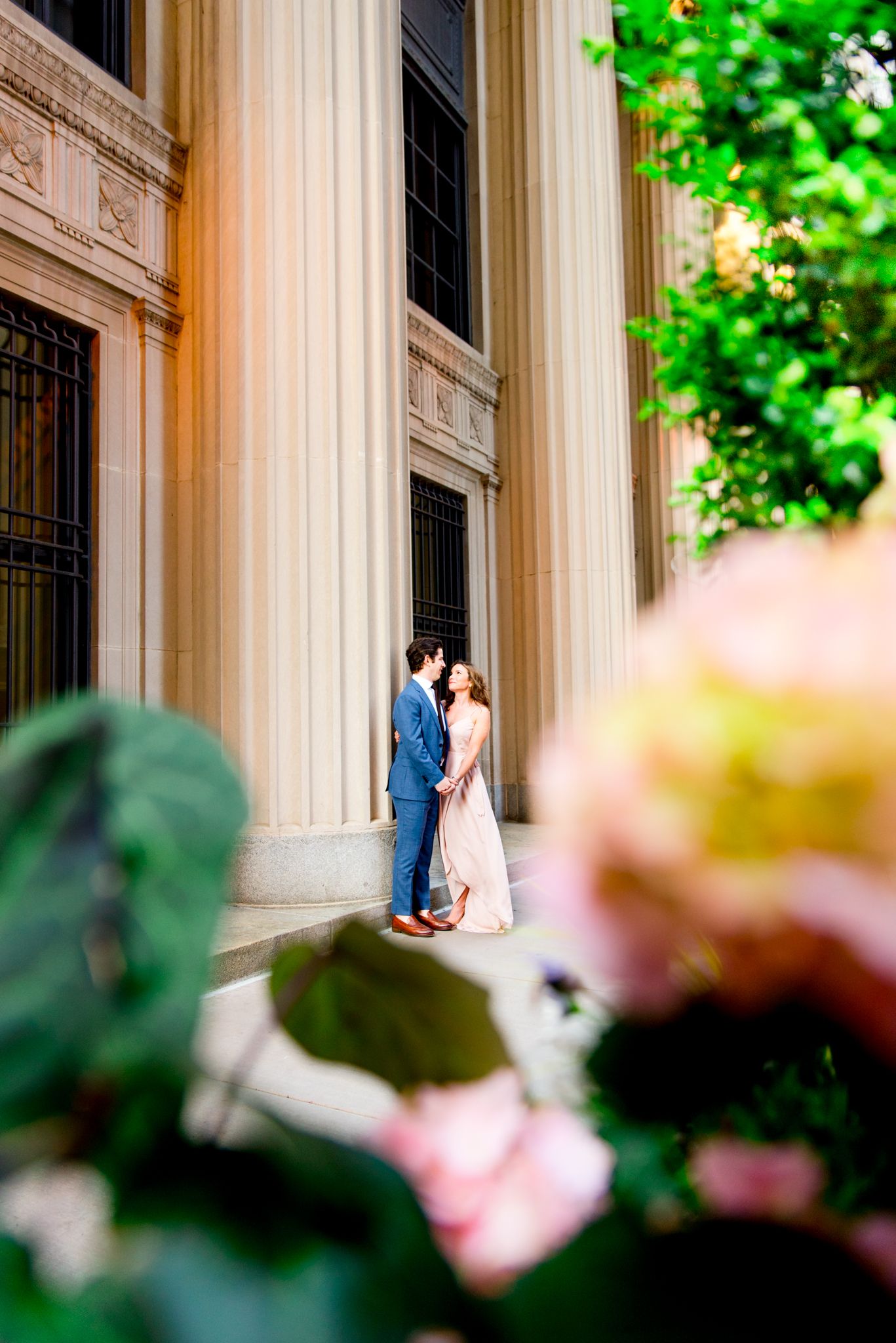 man and woman holding hands looking at each other by the pillars at Chicago Board of Trade for engagement pictures