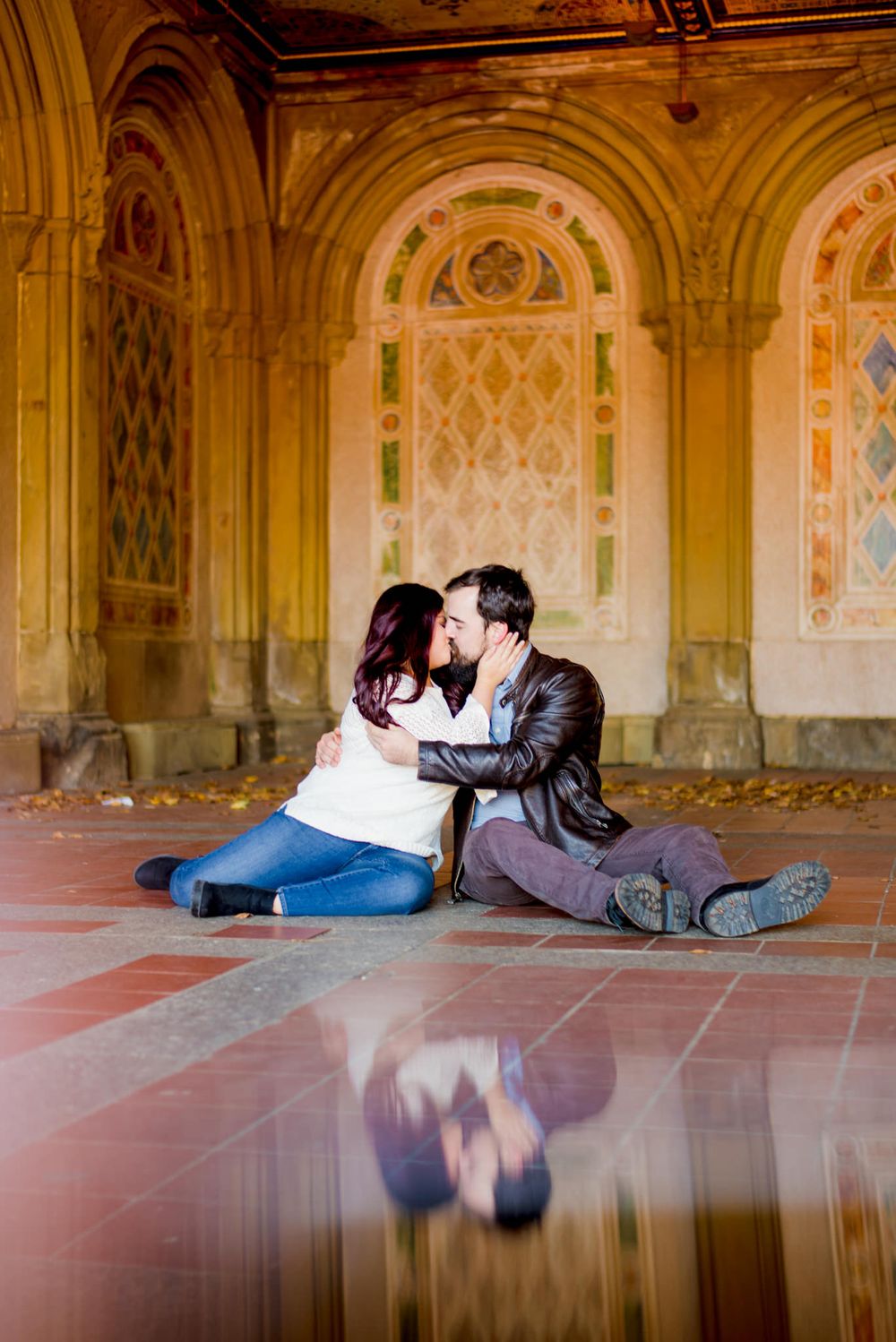 man and woman sitting kissing at Bethesda Terrace and Fountain in Central Park in the fall