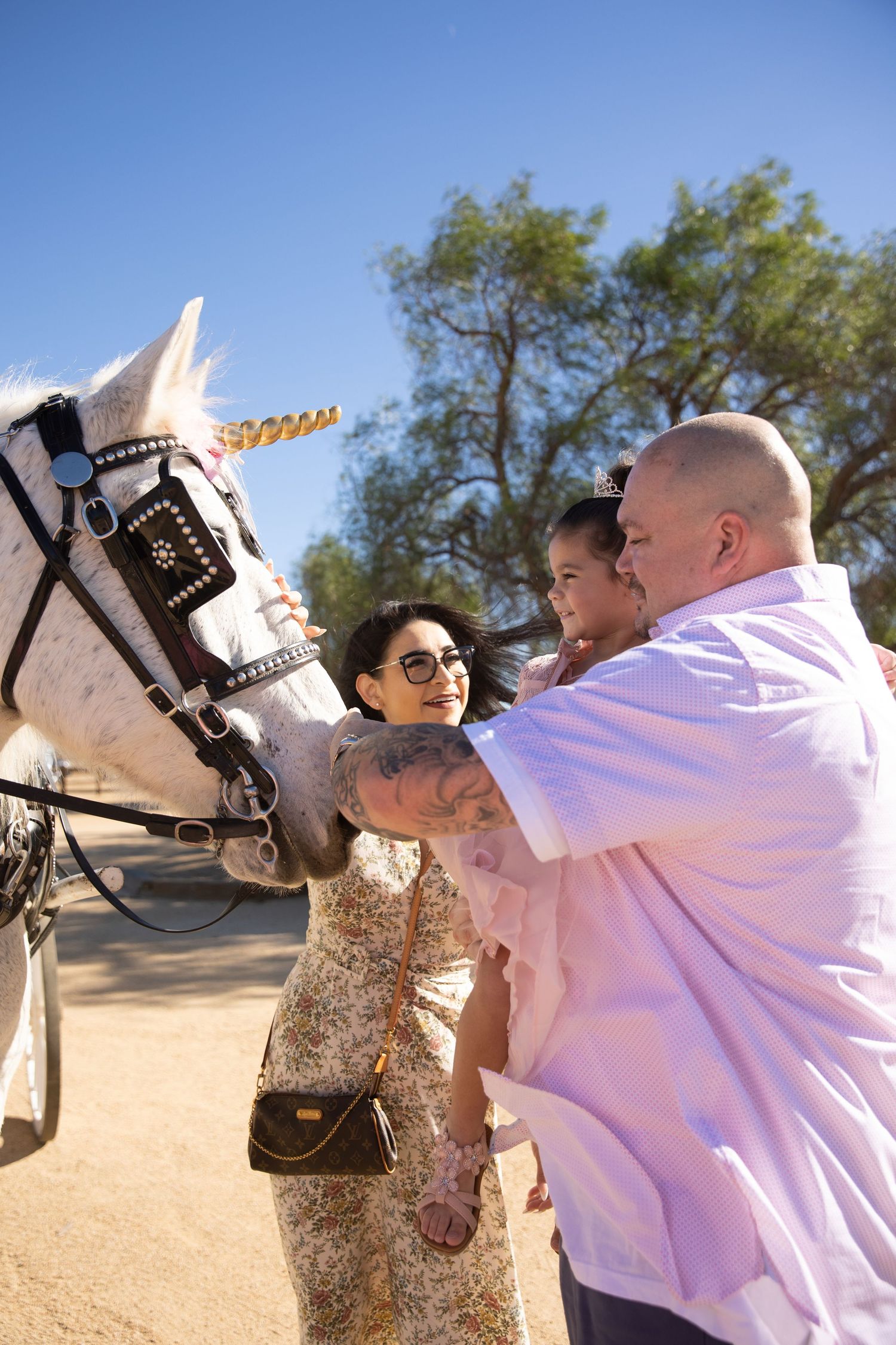 Father, daughter, and mother petting unicorn