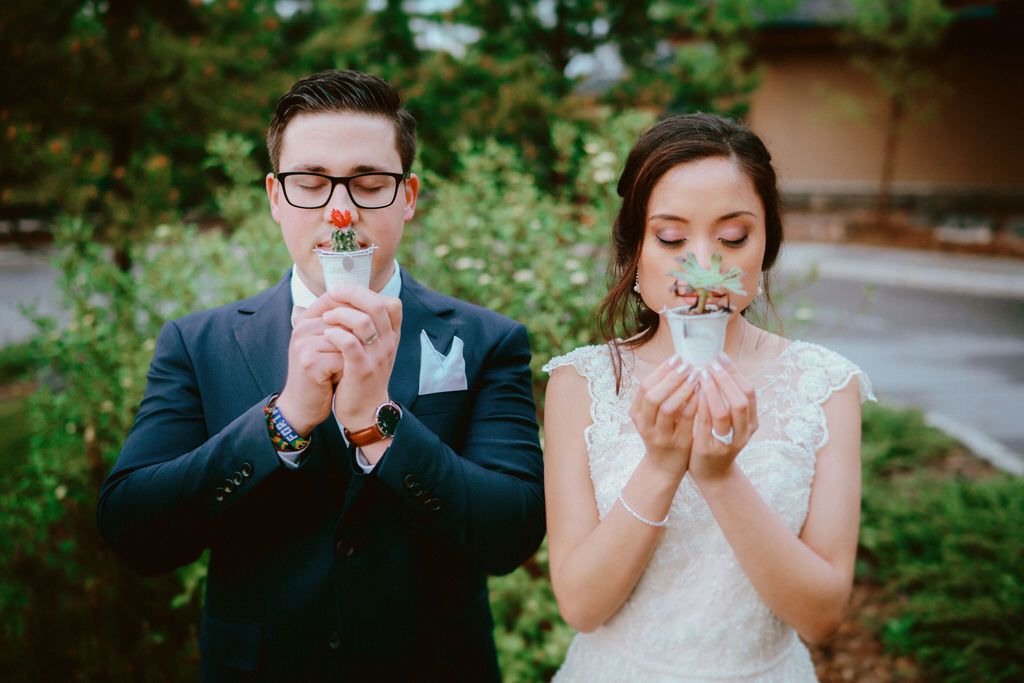 A couple shares playful laughter in a lush garden setting during their wedding portraits.