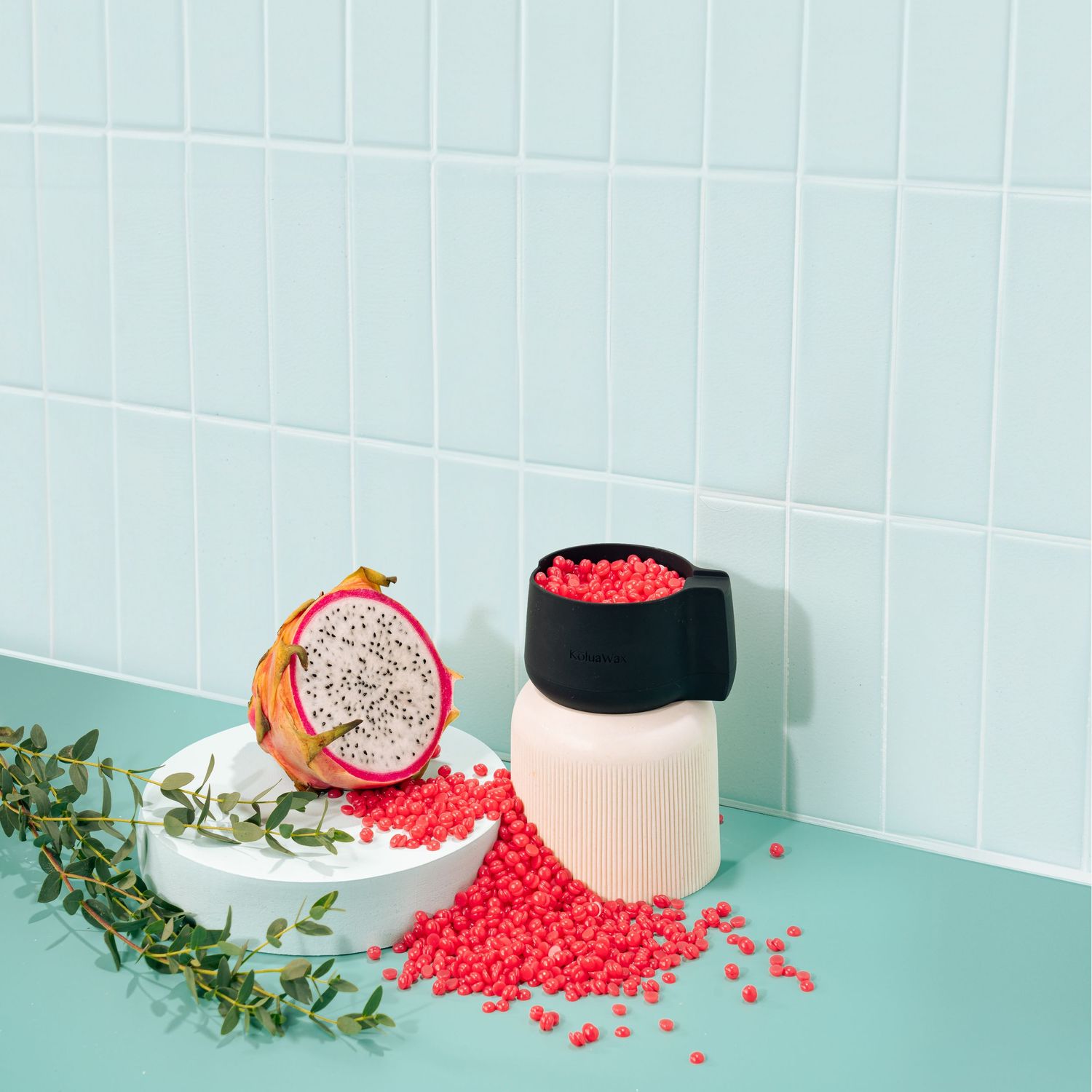 Dragon fruit and red beads arranged with greenery against tiled background.