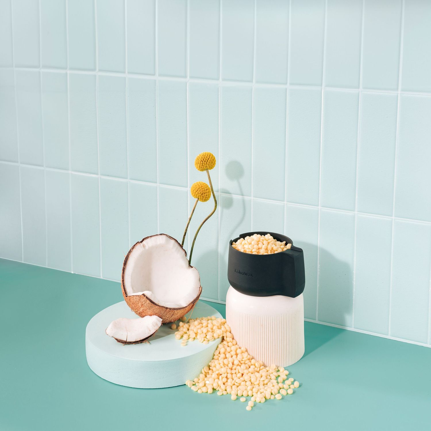 Coconut and yellow flowers arranged with scattered beads and a black and white container.