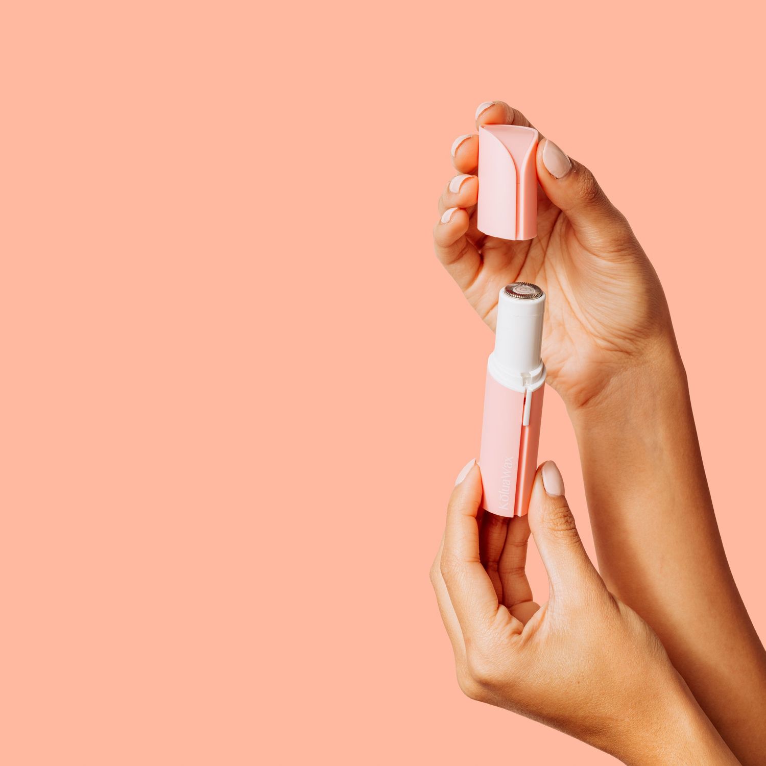 Hands holding pink and white beauty product against coral background.