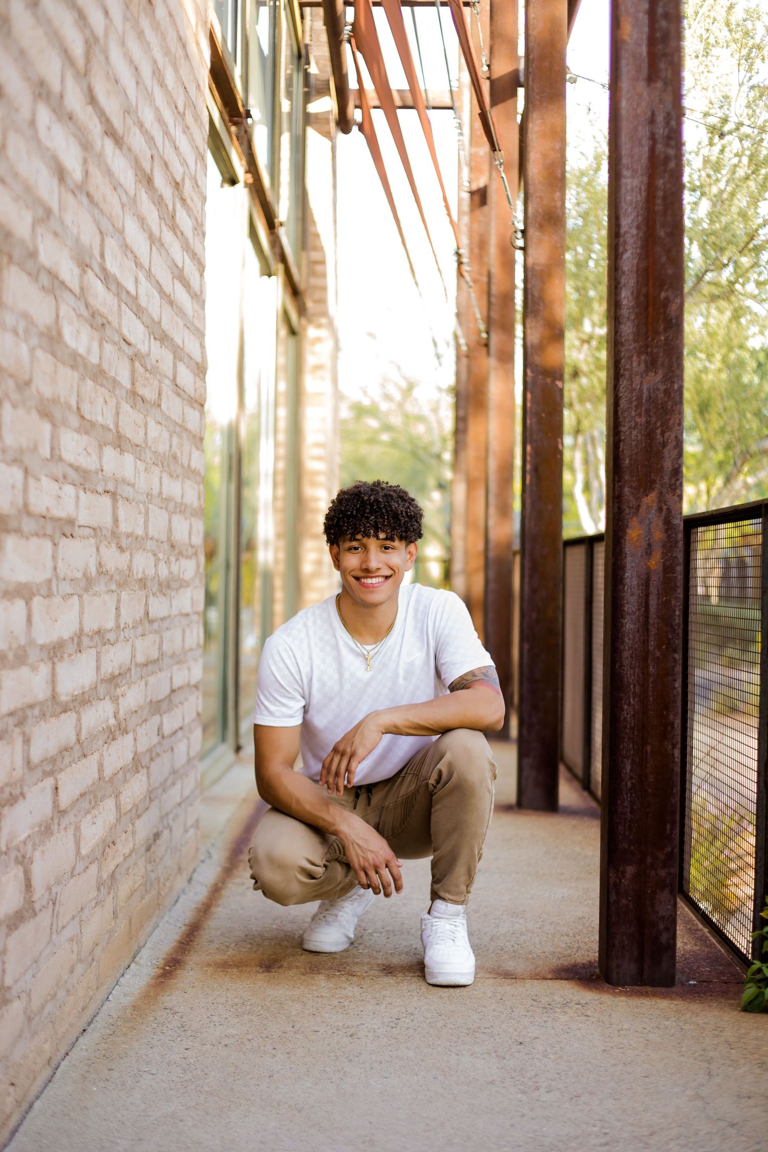 Senior graduate boy kneels down for a cool photo in an urban location for his Senior portraits.