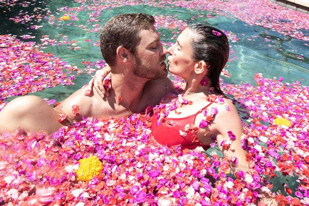A couple kiss in a pool of flowers