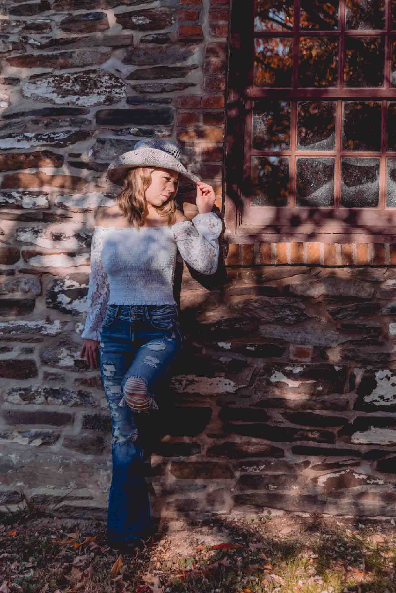 cowgirl posing at the stone house on a working farm