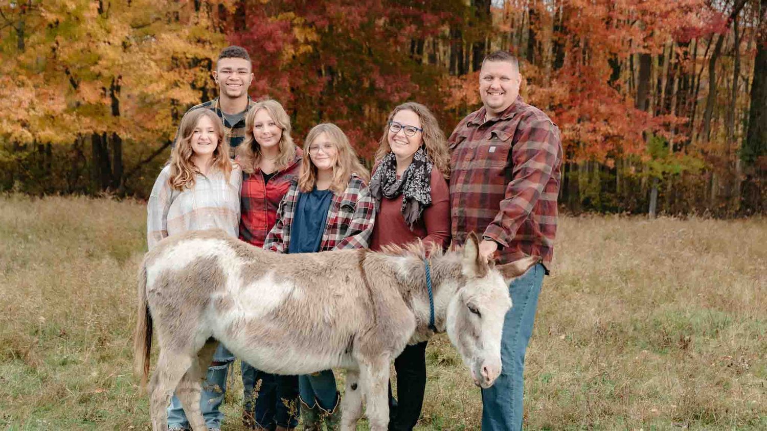family posing for a photo with their pet donkey on their family farm